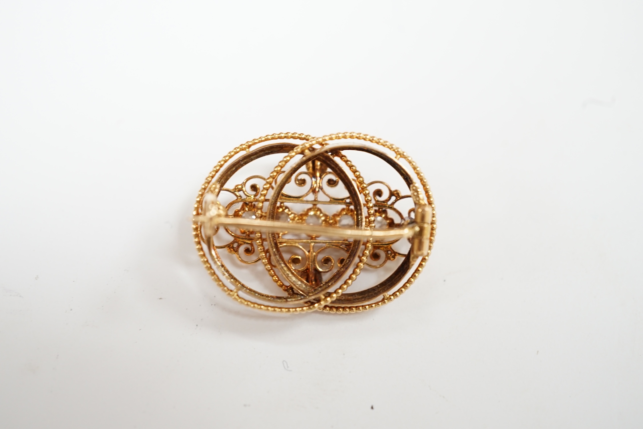 A pierced yellow metal and five stone diamond set double circle brooch, 26mm, gross weight 4 grams. Condition - fair to good